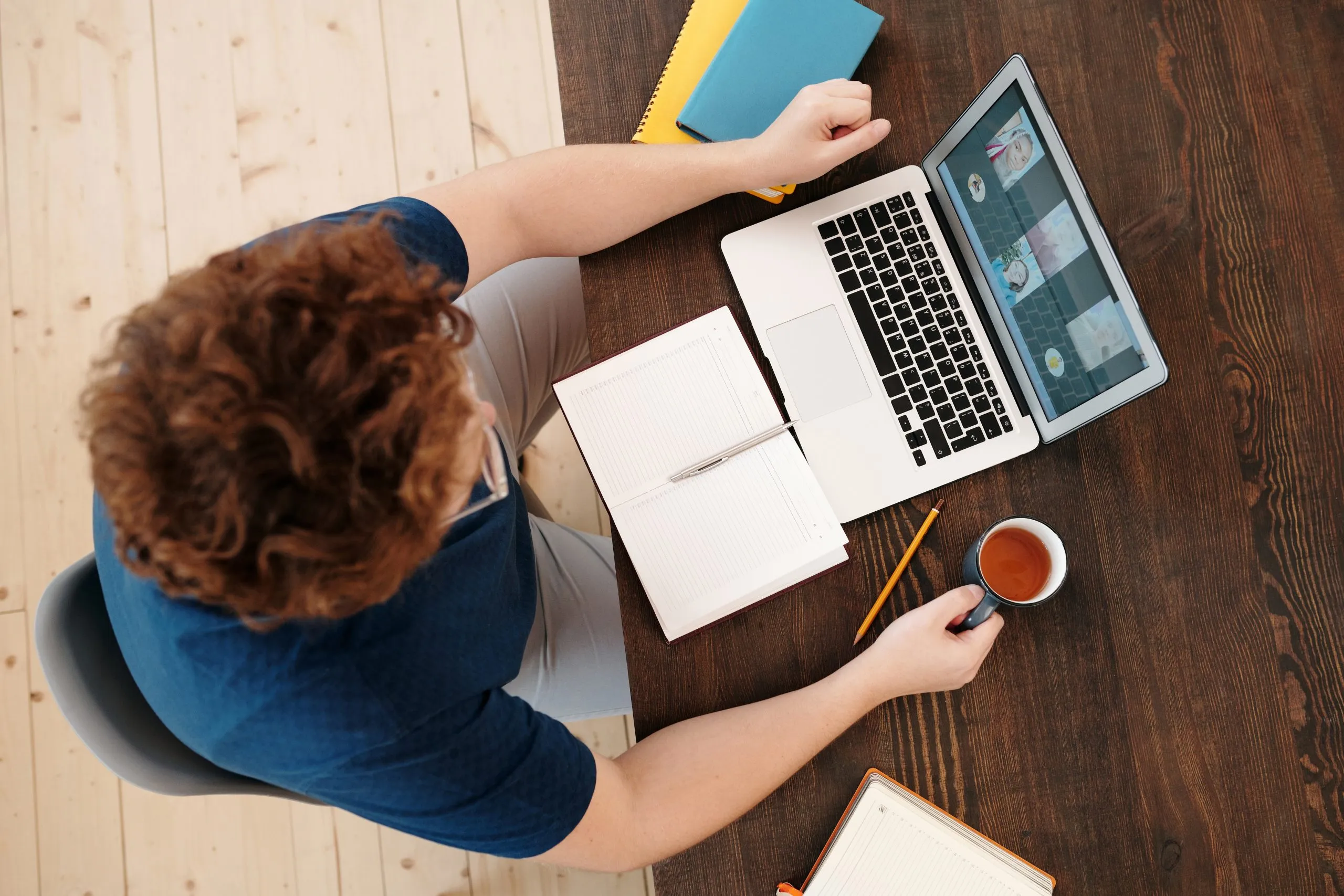 Man on laptop with notebook and hot drink in front of him