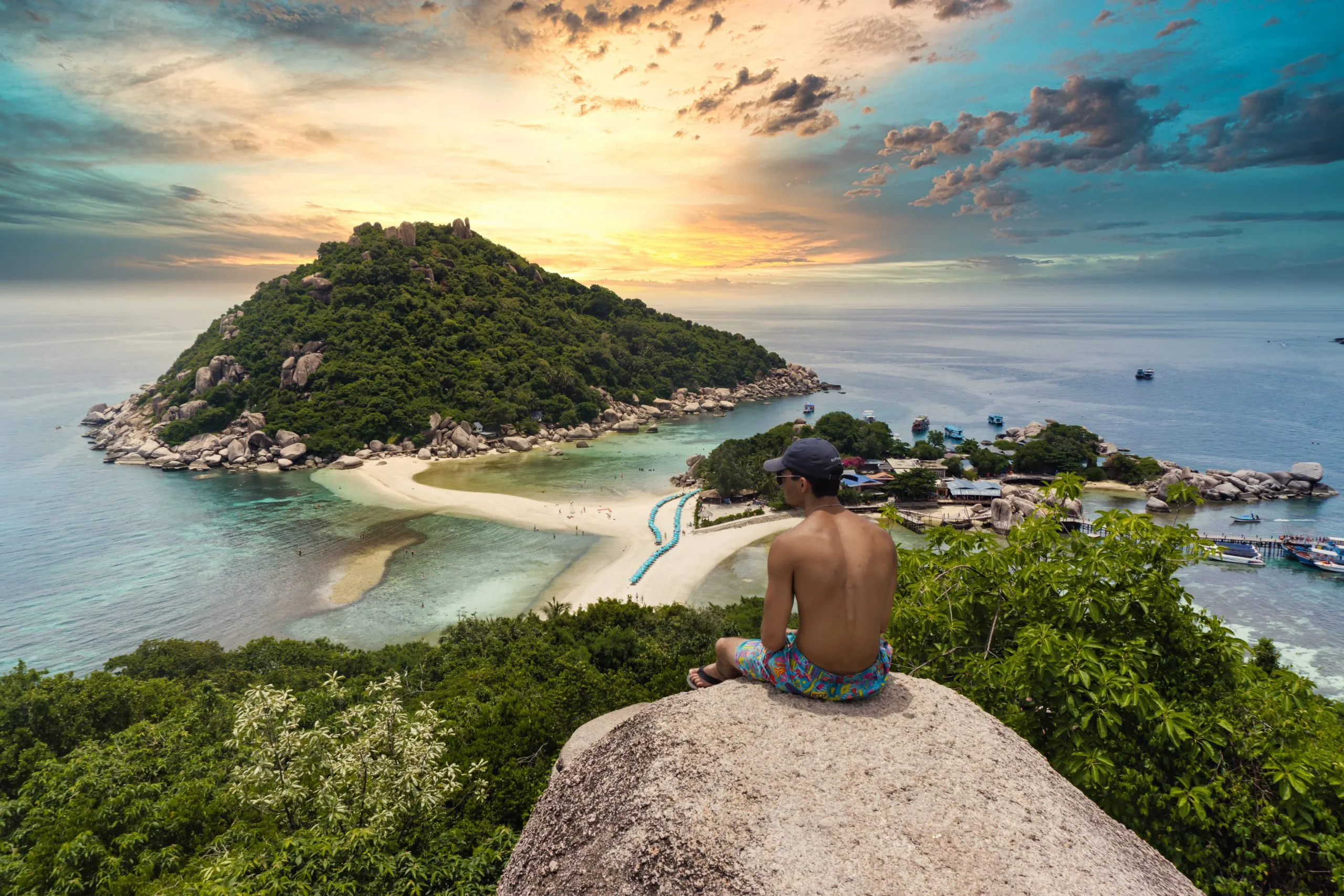 Man sat on a rock looking onto Thai landscape