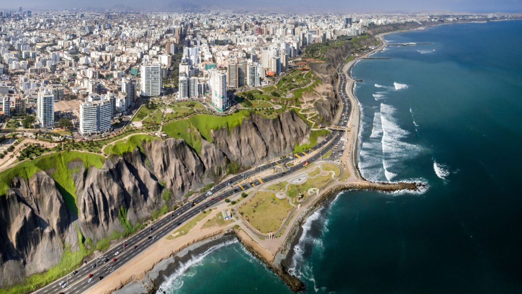 Large road next to the sea with a large city aat the top of the cliff