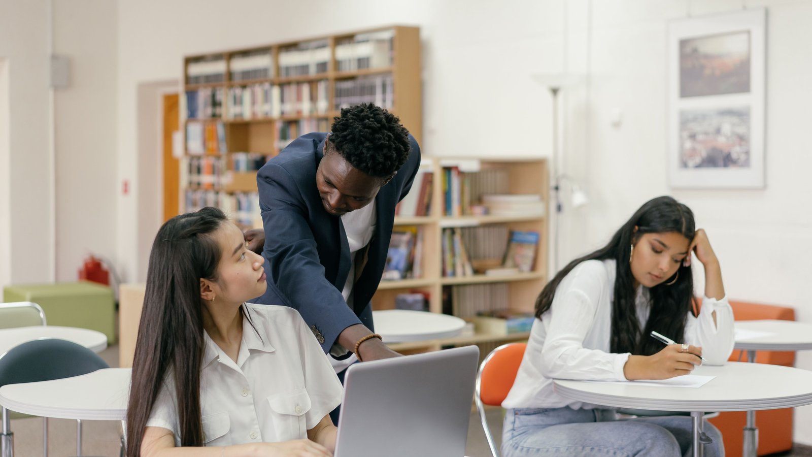 Teacher giving one-to-one error correction in ESL feedback to a student on a laptop