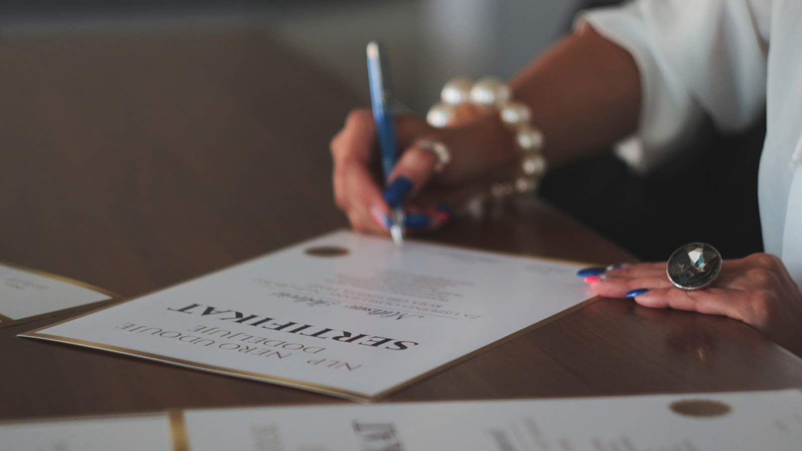 hand signing a certificate document representing tefl certification versus a state teaching license process