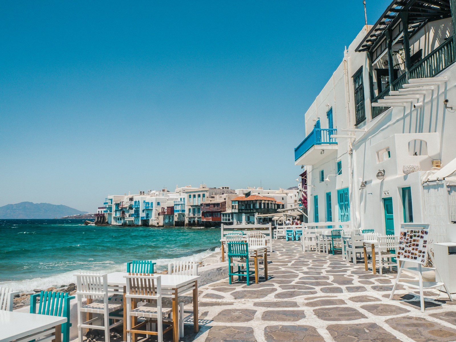 Waterfront cafe tables in a Greek coastal town, where seasonal English teaching work is concentrated