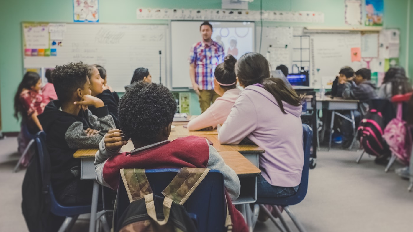 Higher level teaching assistant leading a small group learning activity in a classroom