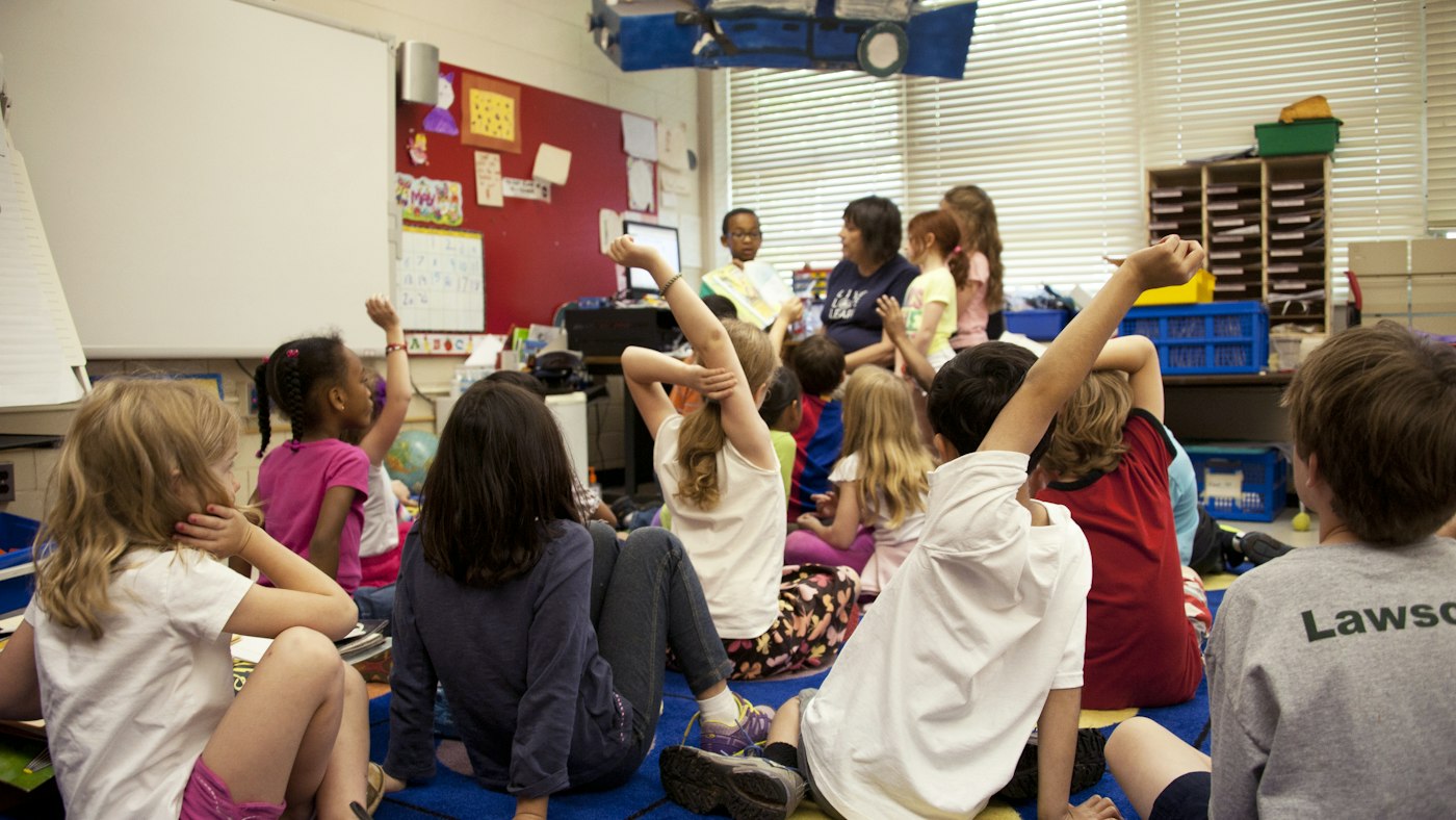 HLTA supporting a teacher during a whole class reading session in a primary school