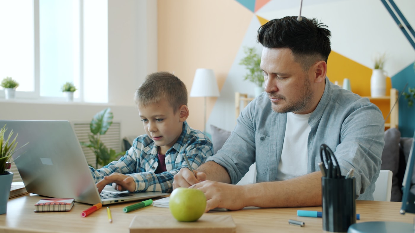 Parent and child together at a laptop during an online English class for young learners