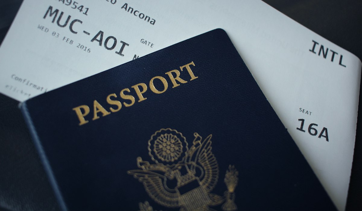 A passport resting on a stack of visa paperwork prepared for an overseas teaching application