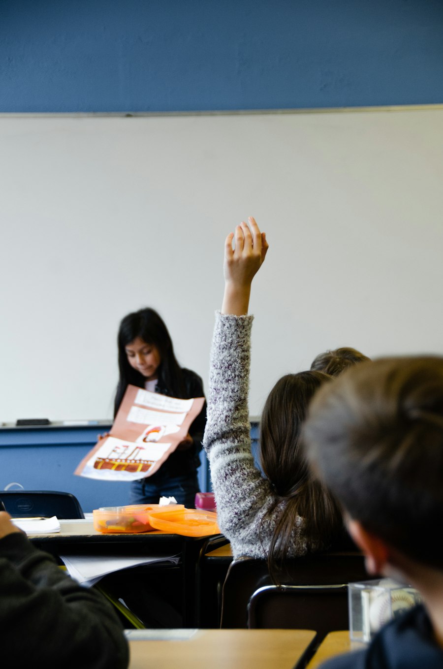 A student raising a hand in class, the kind of moment a bilingual paraprofessional supports