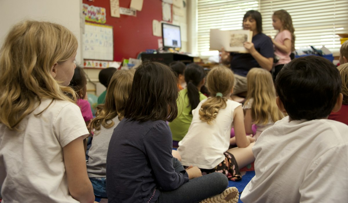 Teacher reading to a class including newcomer English learners identified as SLIFE